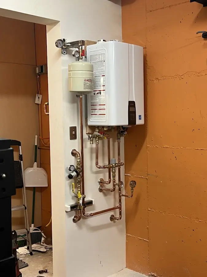 Plumbing technician inspecting water heater connections in Rollin